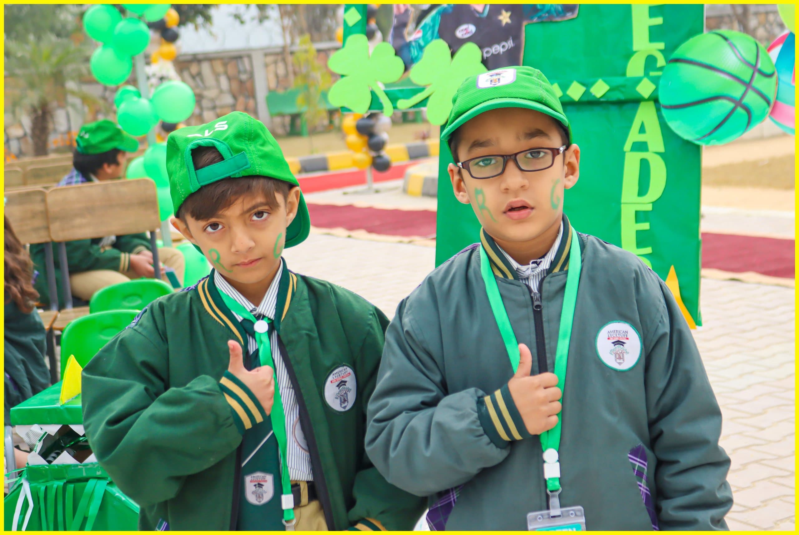 Two students in green school jackets giving a thumbs up