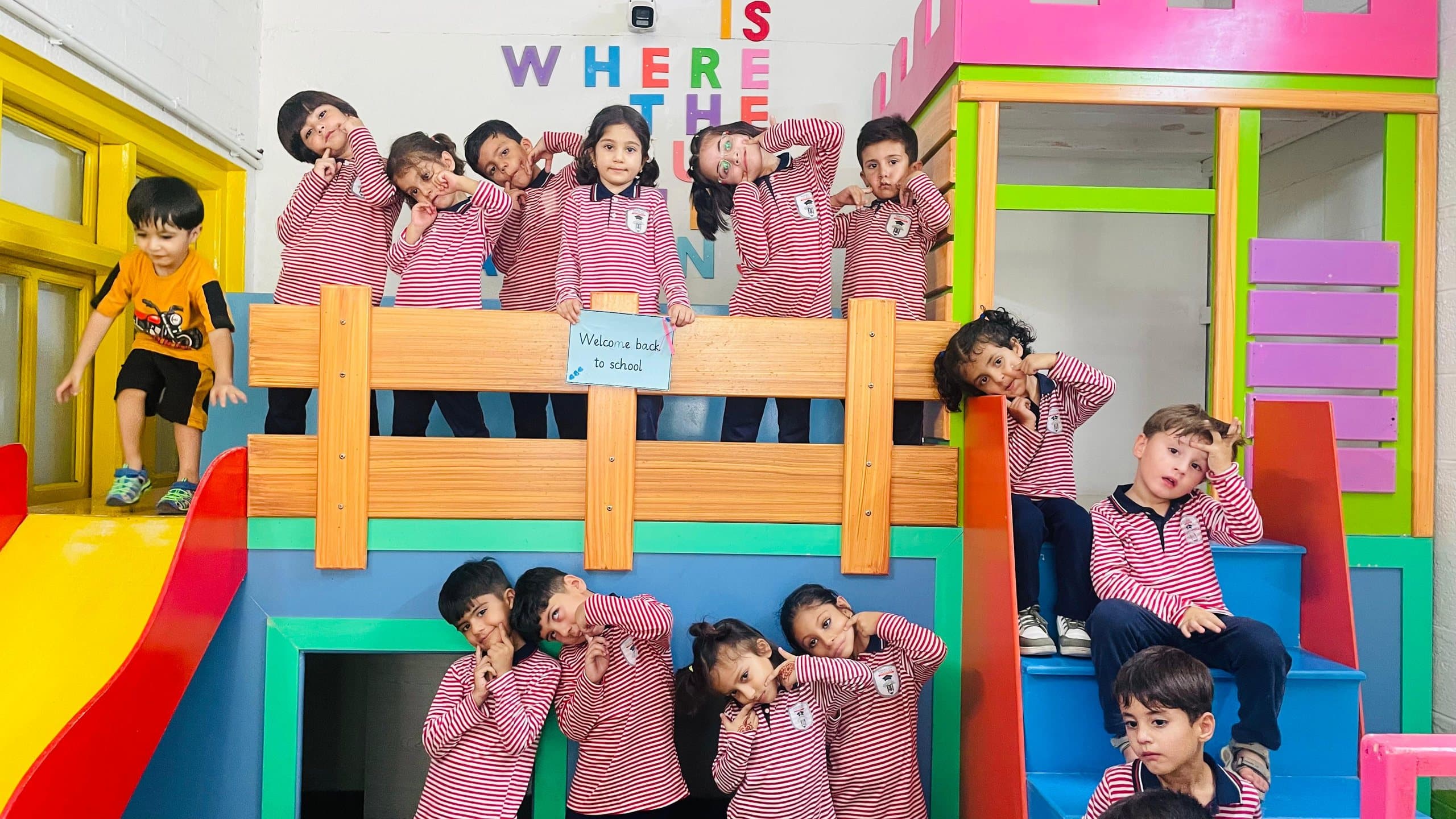 Young students in striped uniforms posing on a classroom play structure