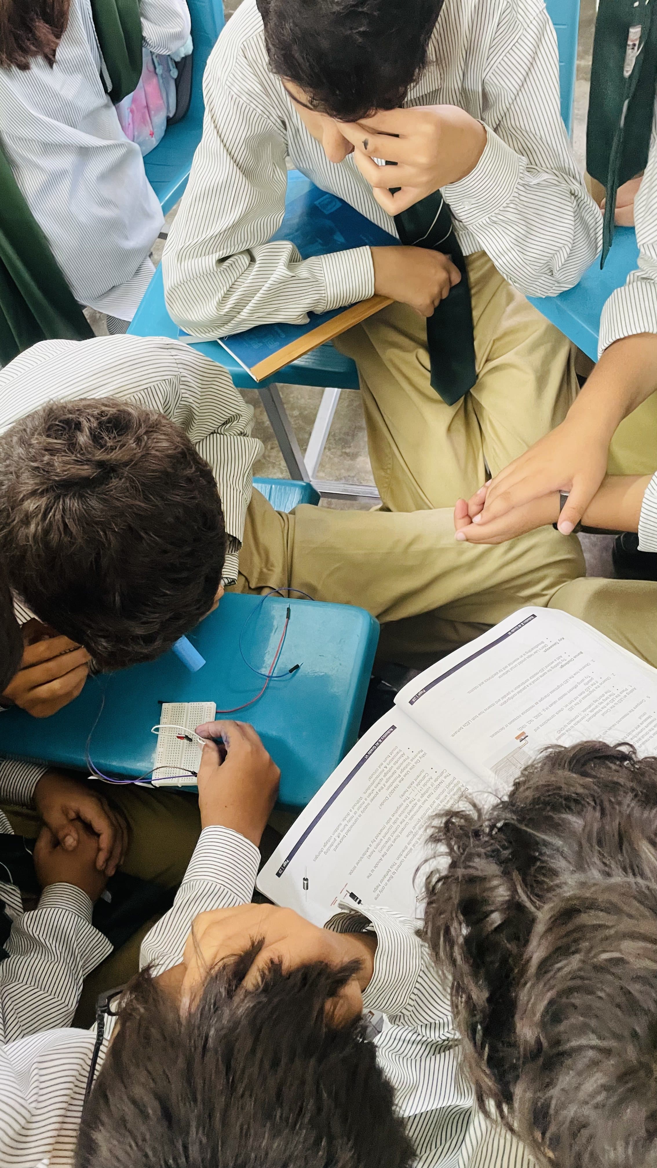Students wiring a breadboard circuit together on a lab desk