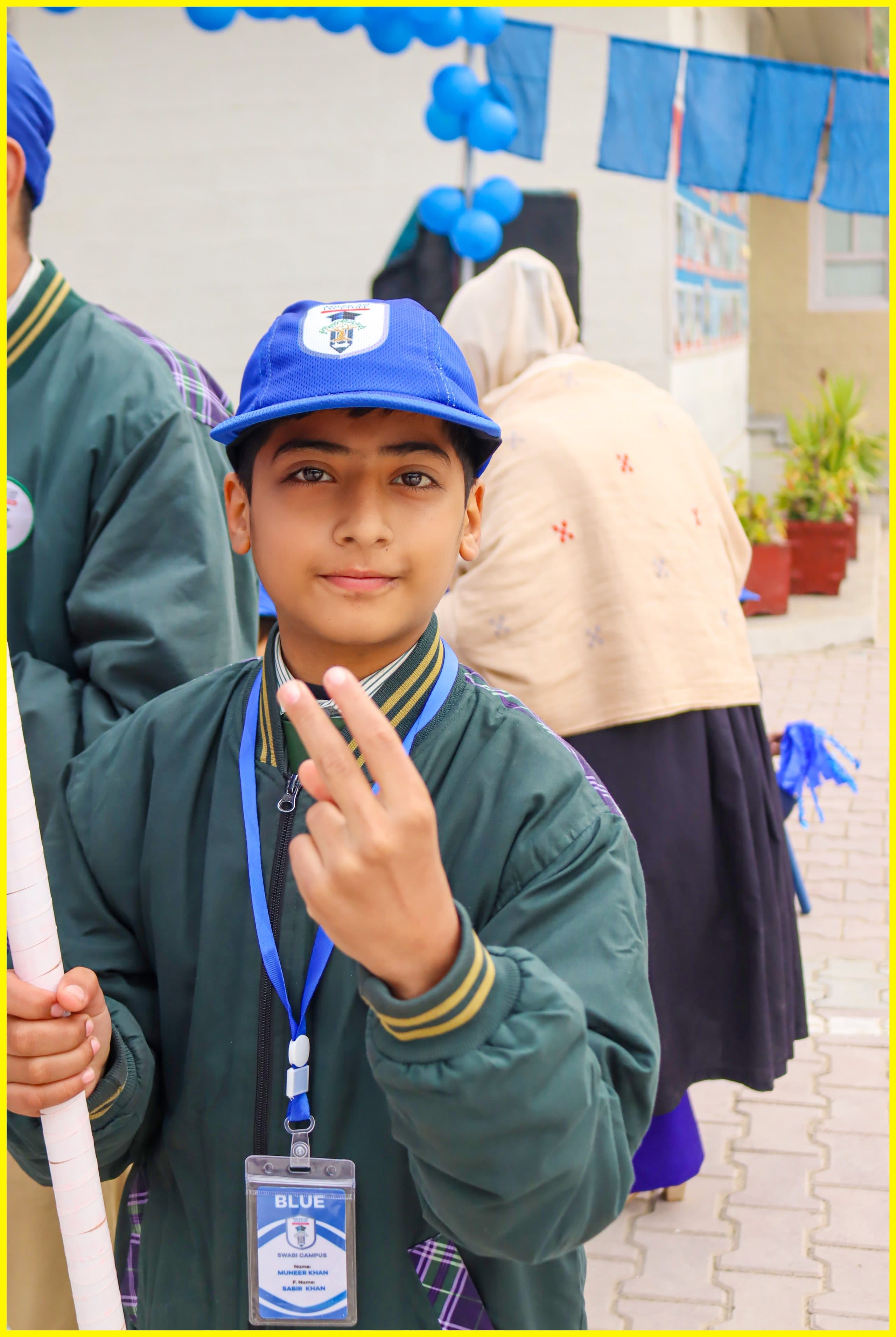 A student in a blue cap smiling outside the robotics laboratory