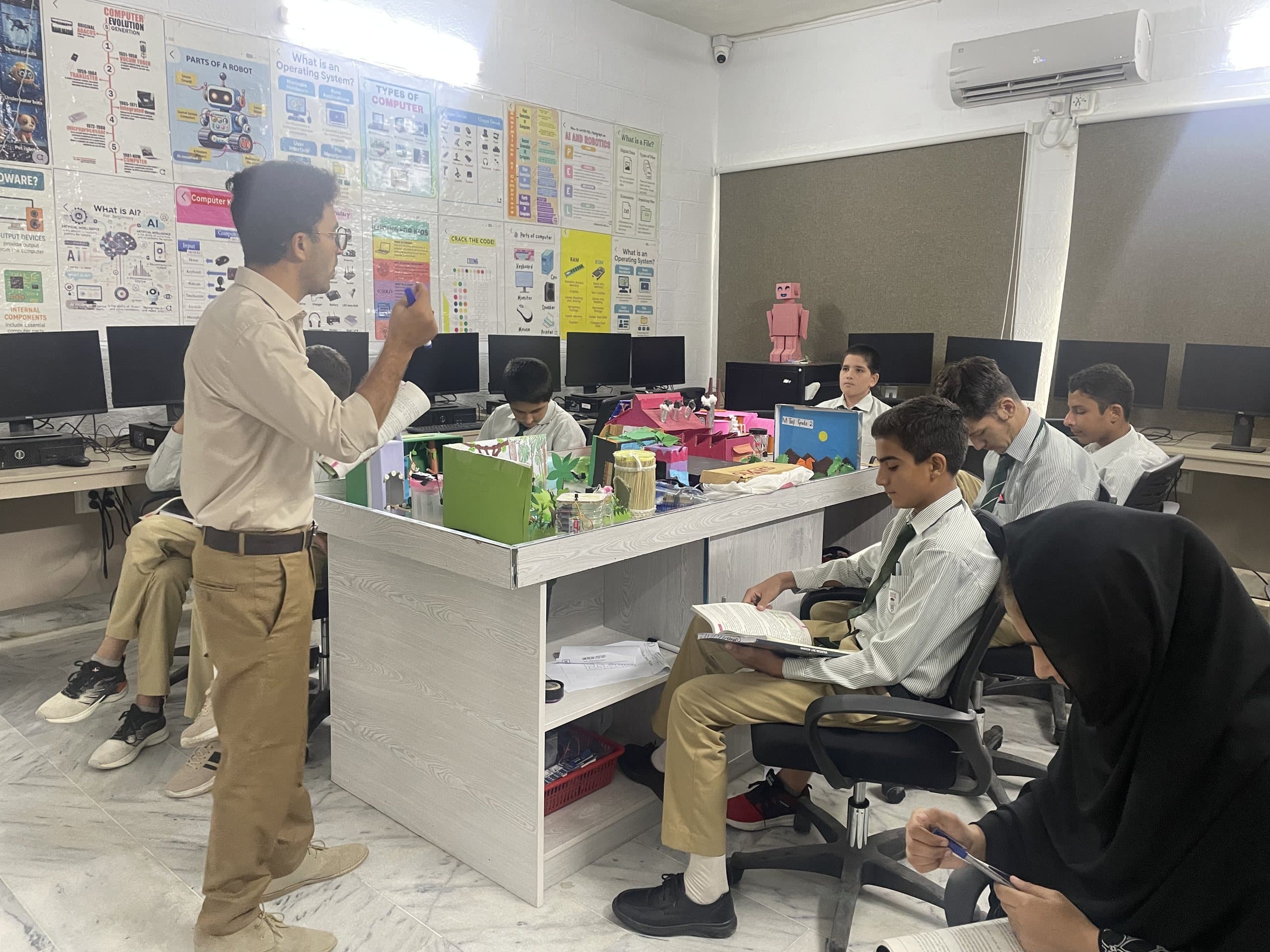 A teacher leading a robotics class while students build projects at their lab benches