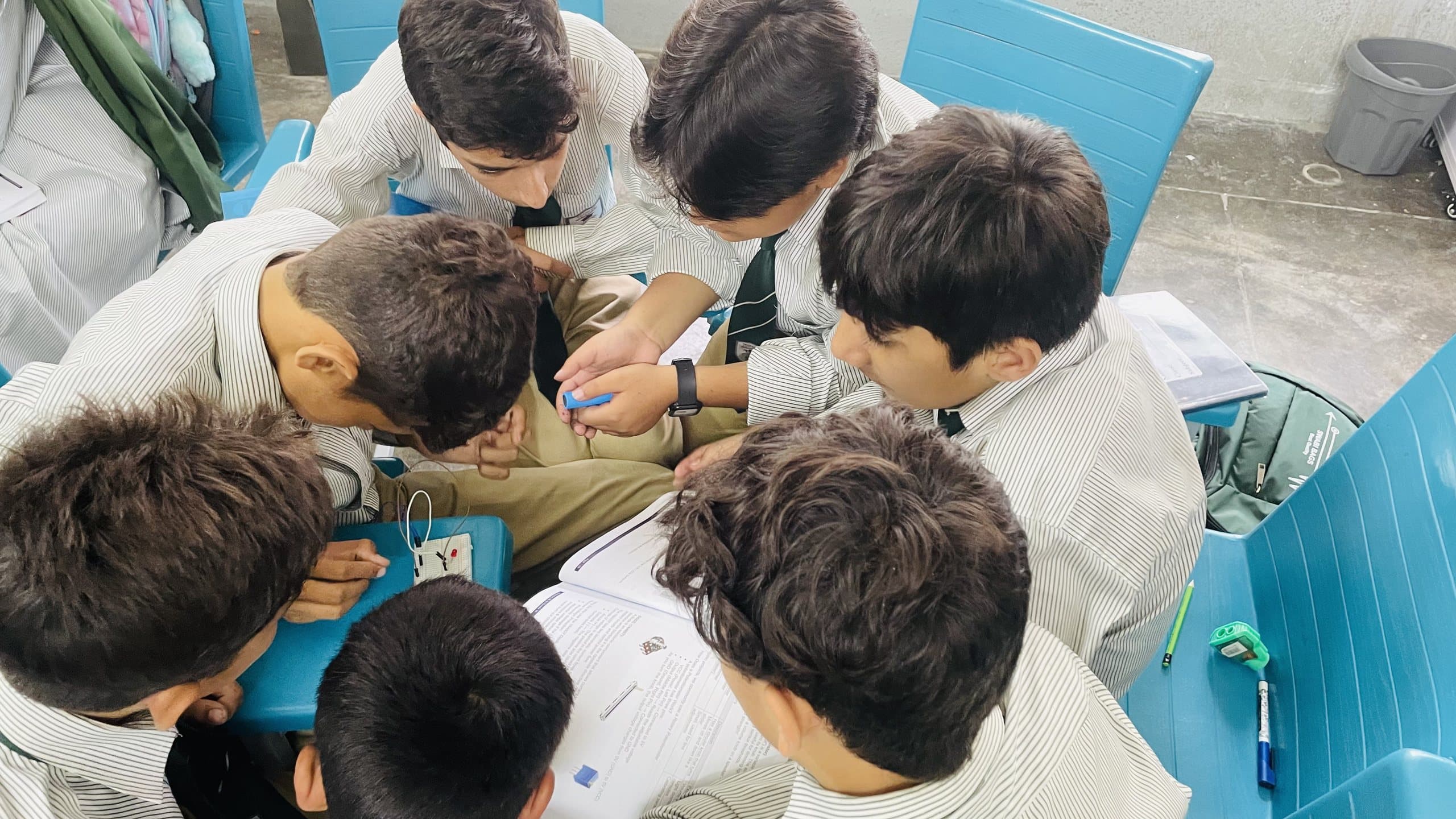 A group of middle school students huddled over a robotics kit